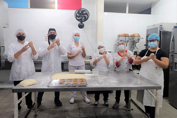 grupo de formación técnico en panificación haciendo la seña que significa SENA en Lengua de señas colombiana.
